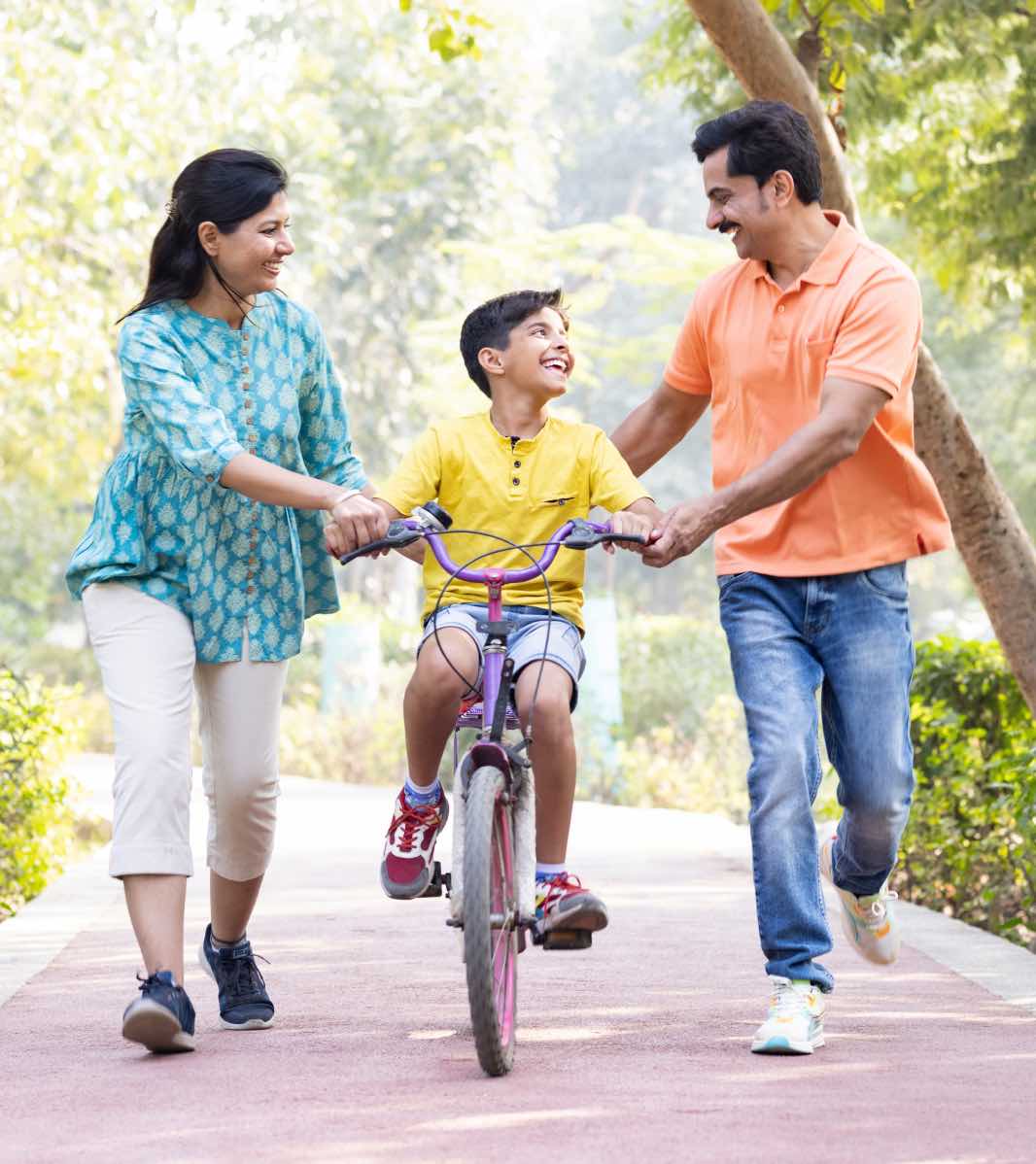 Parents smiling and helping their child to ride a bicycle