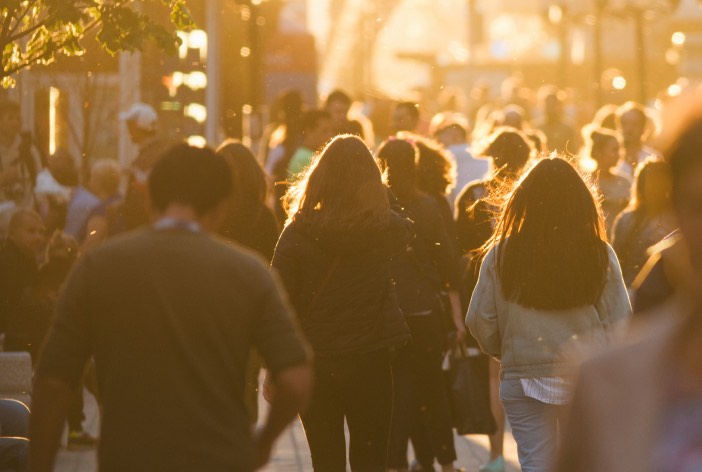 Busy city street at sunset with pedestrians on sidewalk