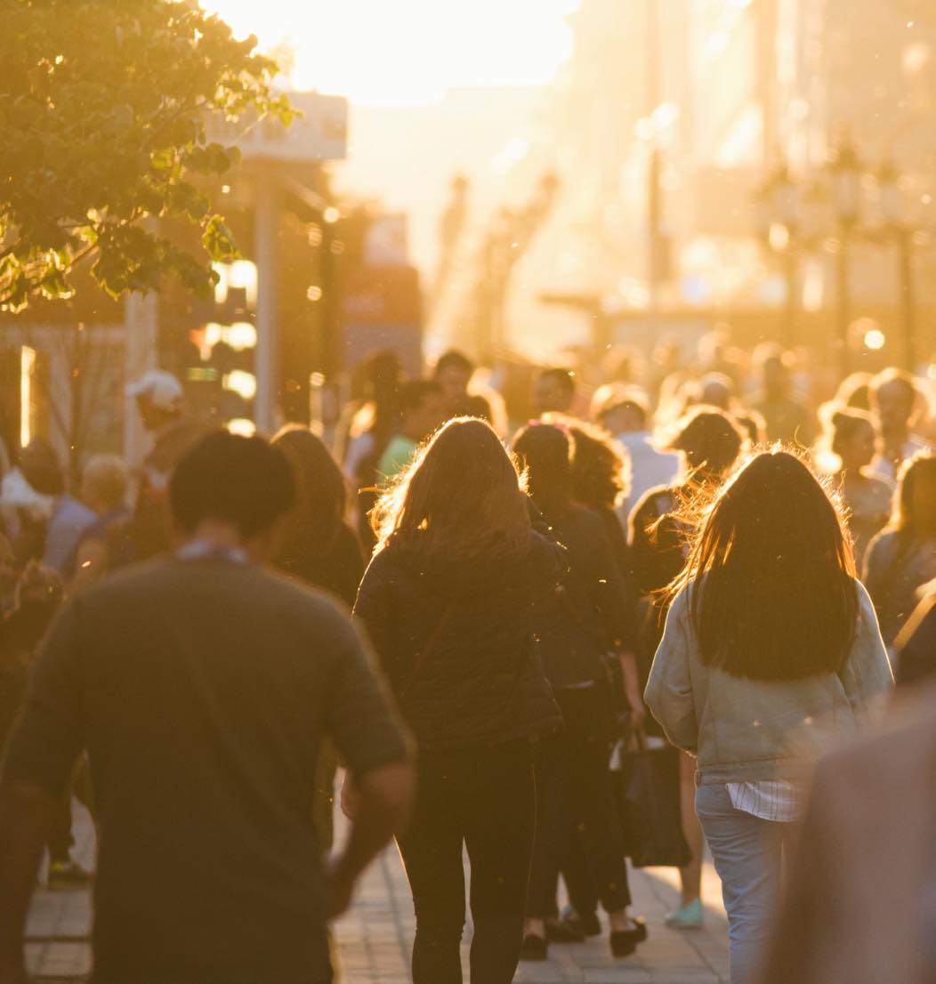 Busy city street at sunset with pedestrians on sidewalk