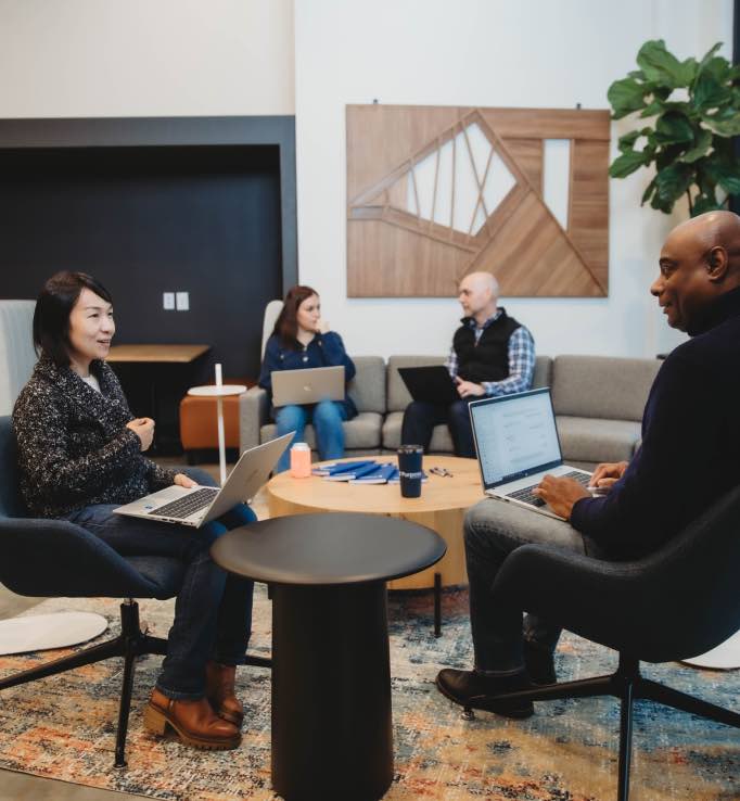 Purpose Financial employees meeting around a table in a common area of the office